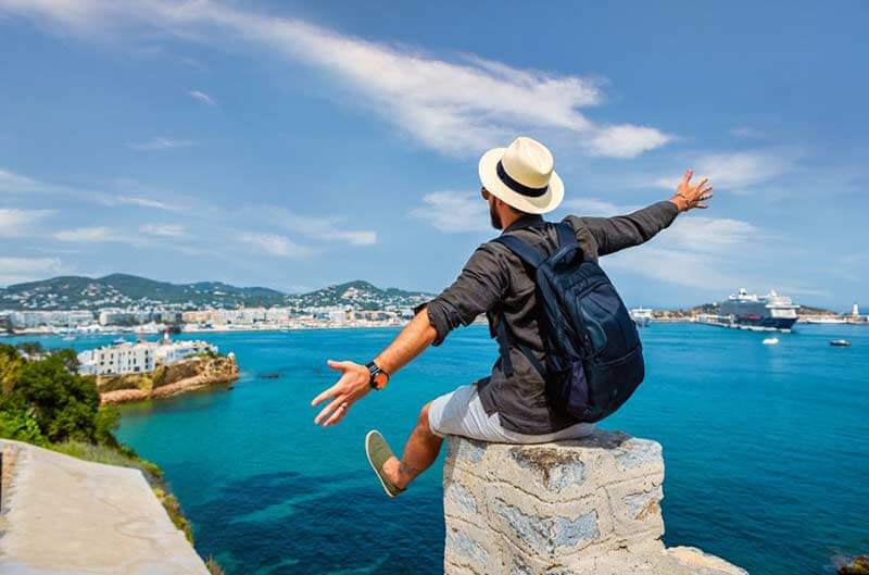 Мan with backpack and hat overlooking harbor with cruise ship